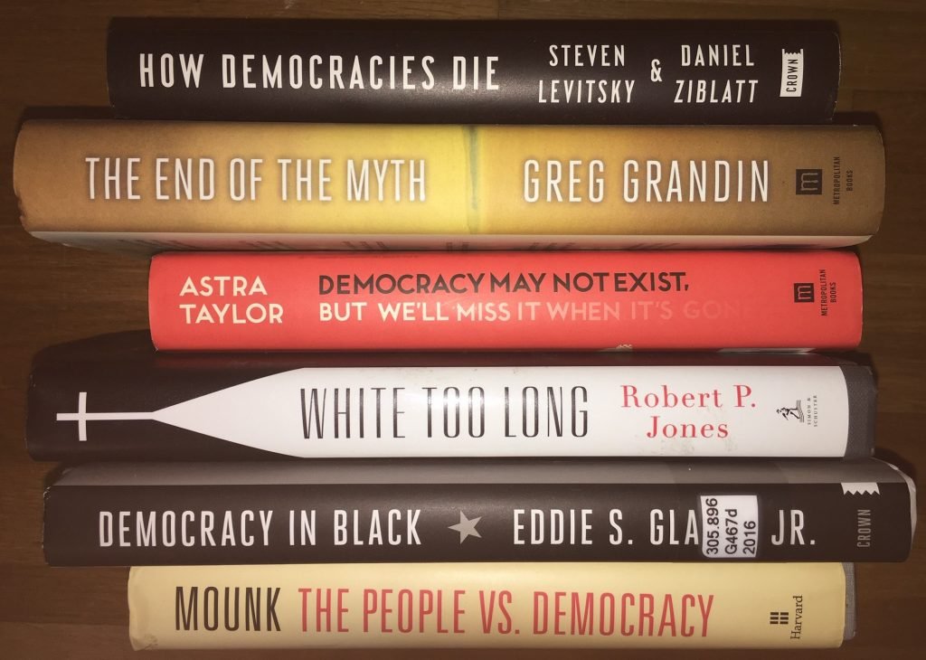 Stack of books on the theme of democracy at risk.