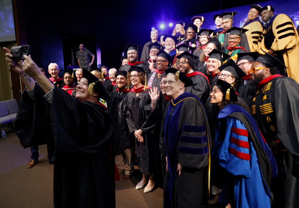 Sara Cunningham, founder of Free Mom Hugs and recipient of an honorary Doctor of Humane Letters degree, takes a selfie with the faculty and graduates after the 2024 Phillips Theological Ceremony commencement ceremony May 18, 2024.